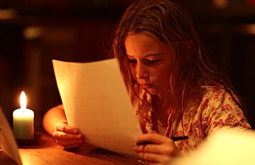 Photo of girl reading by candle light