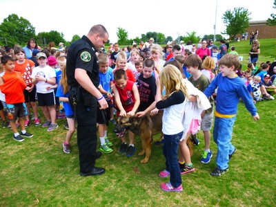 Group of children pet a K-9 dog.